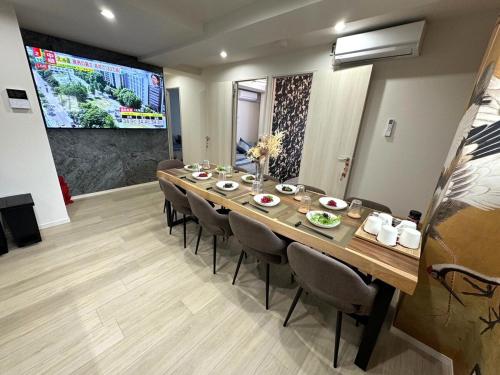ein langer Esstisch mit Stühlen und einem großen Bildschirm in der Unterkunft K square 400 in Nagoya