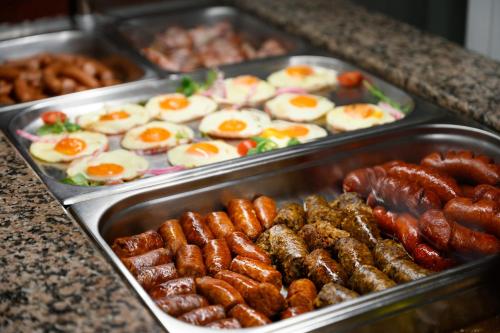 a buffet of food with eggs and sausages and sausage at Thermal Park Hotel Egerszalók in Egerszalók