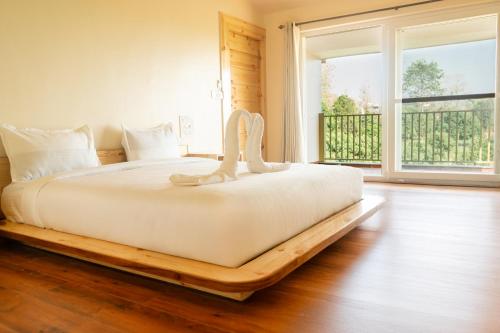 a bed in a room with a large window at Evaan Litchi Orchards and Resorts, Corbett in Rāmnagar