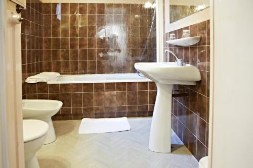 a bathroom with a sink and a tub and a toilet at Hôtel Mets et Plaisirs in Mazamet