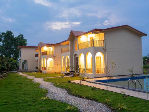 a large house with a pool in front of it at Evaan Litchi Orchards and Resorts, Corbett in Rāmnagar