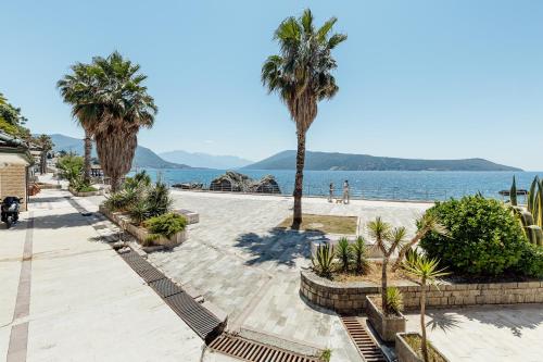 a walkway next to the water with palm trees at Swisslion Studios in Herceg-Novi