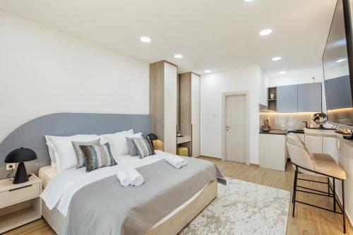 a bedroom with a large white bed and a kitchen at Swisslion Studios in Herceg-Novi