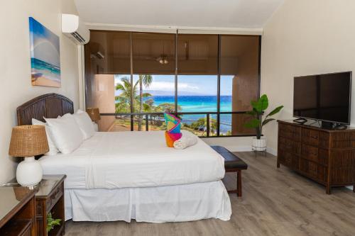 a bedroom with a white bed with a television and a bed sidx sidx at Oceanview Kahana Villa - Walk to Beach & Dining in Kahana