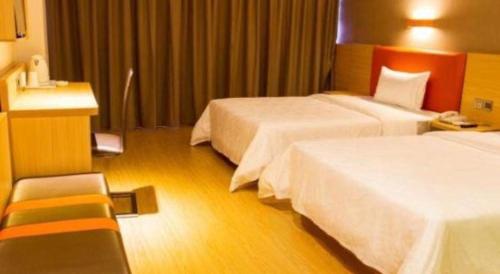 a hotel room with two beds and a chair at 7 Days Premium Zhuhai Gongbei Light Railway Branch in Zhuhai