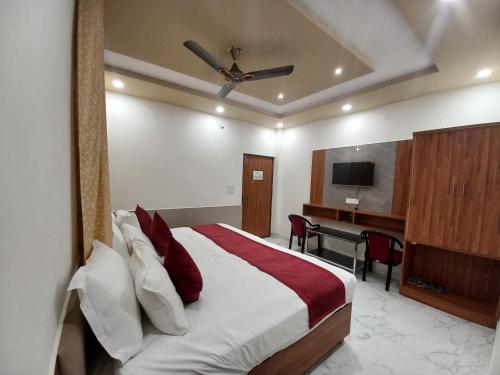 a bedroom with a bed and a desk and a television at Hotel Aaradhya Residency in Agra