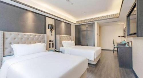 a hotel room with two beds and a desk at Xana Hotelle Zhuhai Gongbei Port in Zhuhai