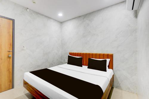a bedroom with a large bed with white walls at Hotel O Lotus in Surat