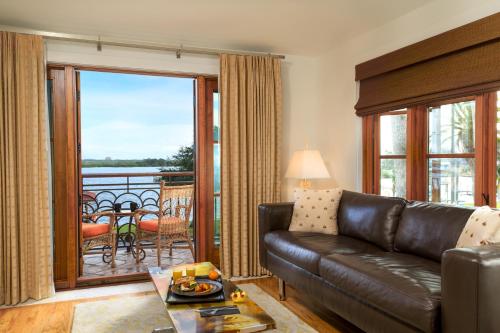 a living room with a leather couch and a balcony at Black Dolphin Inn in New Smyrna Beach