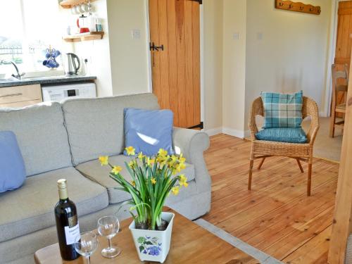 un salon avec un canapé et une table avec des fleurs dans l'établissement Blenheim Cottage-19652, à Peasmarsh