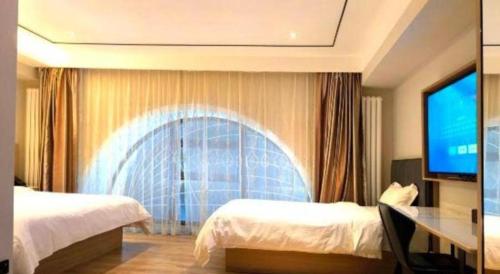 a hotel room with two beds and a flat screen tv at GreenTree Inn Harbin Central Avenue in Harbin