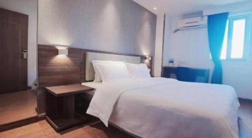 a bedroom with a large white bed and a table at 7 Days Inn Guilin Beiji Plaza Yushan Garden in Guilin