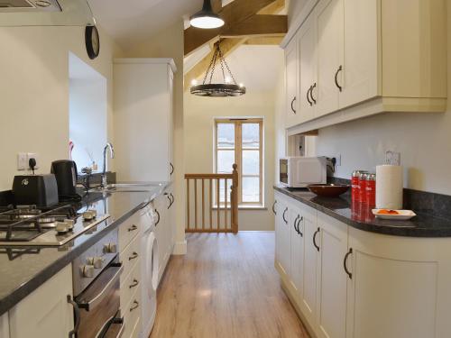 a large kitchen with white cabinets and black counter tops at The Granary in Tiverton