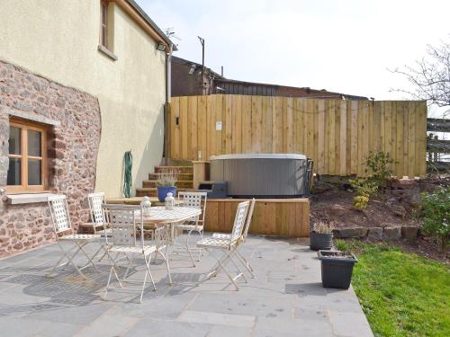 a patio with chairs and a table and a fence at The Granary in Tiverton