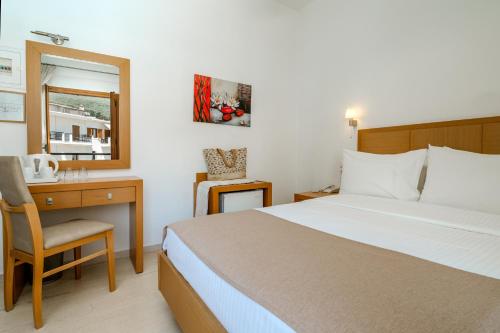 a bedroom with a bed and a desk and a window at Hotel Rezi in Parga