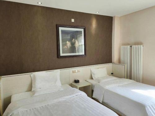 a bedroom with two beds and a picture on the wall at 7 Days Inn Zhangjiakou Chongli Yuxing Road in Zhangjiakou