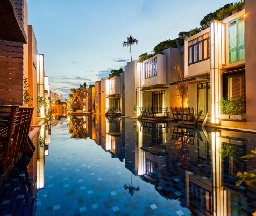 a city street with buildings and a reflection in the water at Let's Sea Hua Hin Al Fresco Resort in Hua Hin