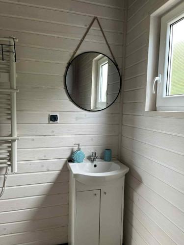 a white bathroom with a sink and a mirror at "Morze Spokoju" domki letniskowe in Darlowko