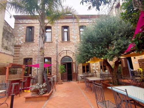 un patio extérieur avec tables et chaises et un bâtiment dans l'établissement El Castell Embruixat, à Saint-Hippolyte