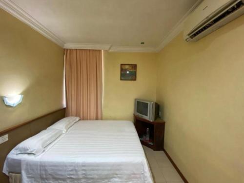 a small bedroom with a bed and a tv at OYO 89958 Hotel Umimas in Lahad Datu