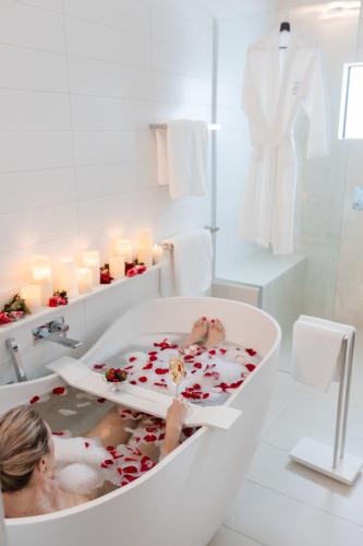 a woman sitting in a bath tub in a bathroom at Luxury Couples Escape - Vue One in Nelson Bay