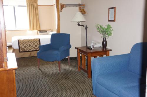 a hotel room with a bed and two blue chairs at Luxury Inn & Suites in Silverthorne