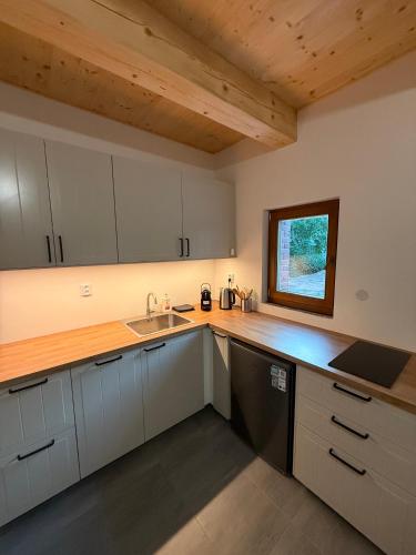 a kitchen with white cabinets and a sink and a window at Sklep Sklenka in Brod nad Dyjí