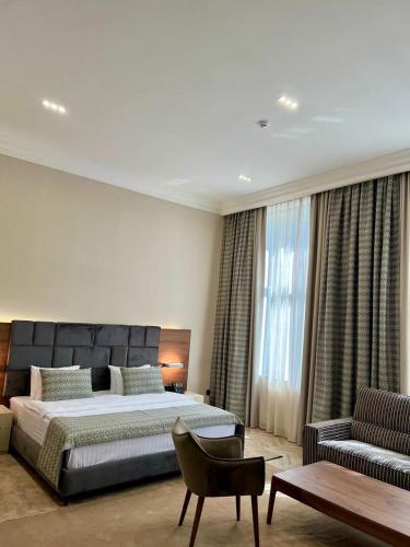 a bedroom with a bed and a chair and a couch at Plaza Viktoria Hotel Yerevan in Yerevan