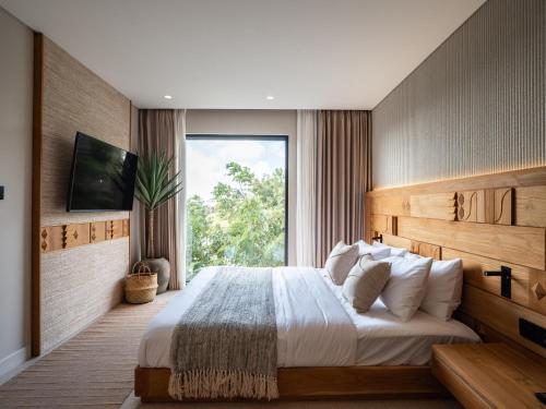 a bedroom with a large bed and a large window at Mira Hotel and Recovery in Uluwatu