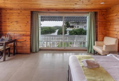 a bedroom with a bed and a large window at Stone Wood Riverfront Resort, Siolim in Siolim