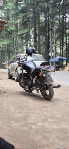 a motorcycle is parked next to a car at Blabla House Himachal in Pulga
