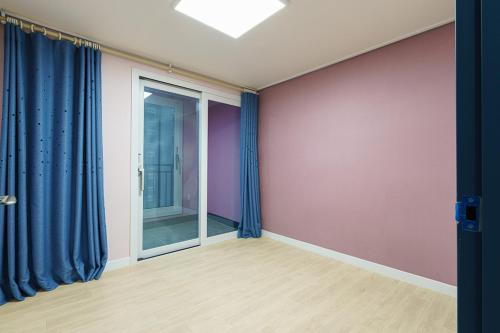 an empty room with purple walls and blue curtains at Little Prince Hotel&Condo in Gunsan