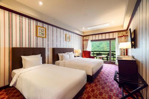a hotel room with two beds and a balcony at KensingtonHotel Seorak in Sokcho