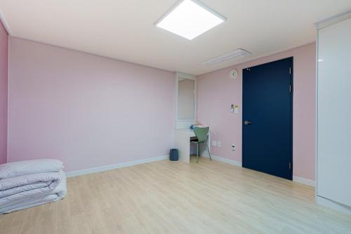 an empty room with a blue door and a chair at Little Prince Hotel&Condo in Gunsan