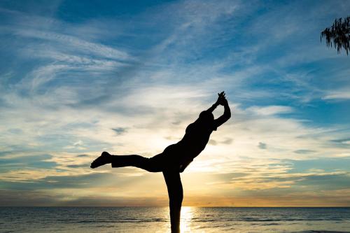 a man doing a yoga pose on the beach at Let's Sea Hua Hin Al Fresco Resort in Hua Hin