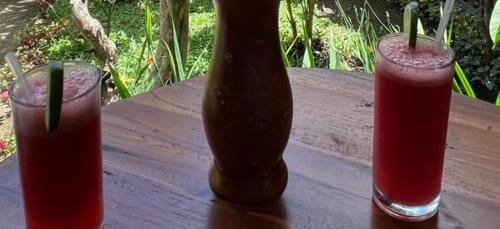 a table with two drinks and a vase on it at Rumah Tenun in Karangasem