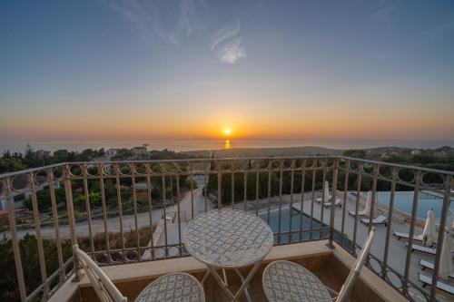a balcony with a table and chairs and a sunset at THISEFS luxury apartments Kefalonia in Antipata