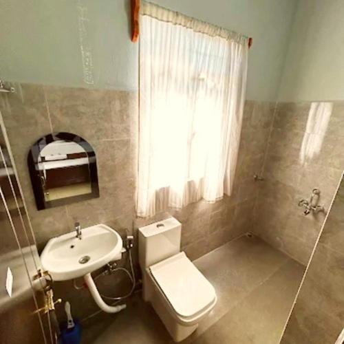 a bathroom with a toilet and a sink and a window at DELI-BAIAR guest house in Mawlynnong