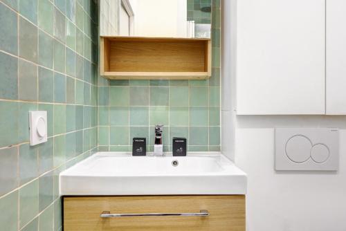 La salle de bains est pourvue d'un lavabo blanc et de carrelage vert. dans l'établissement 245 Suite Mercedes - Superb apartment in Paris, à Paris