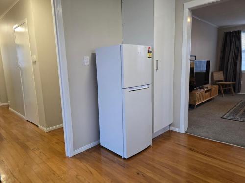a white refrigerator in a room with a living room at Cosy 3 Bedroom home in Auckland in Auckland