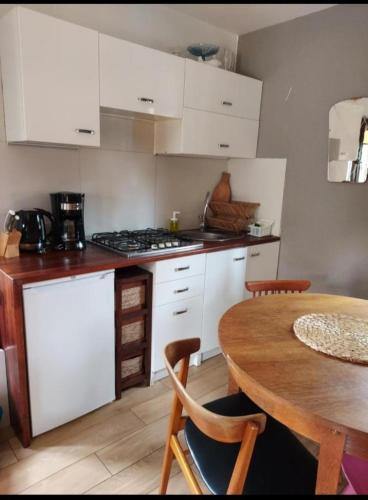 a kitchen with white cabinets and a wooden table at Sosnowy domek in Pobierowo