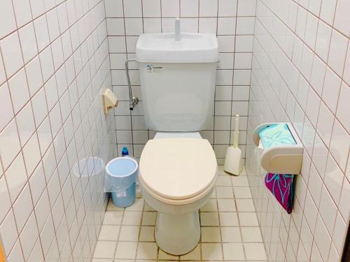 a bathroom with a white toilet in a tiled wall at terrace sakashita in Naha