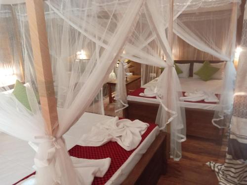 a bedroom with two beds with mosquito nets at Kolon Resort Sigiriya in Sigiriya
