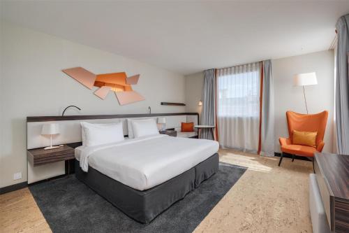 a hotel room with a bed and a chair at Radisson Blu Hotel, Paris Boulogne in Boulogne-Billancourt
