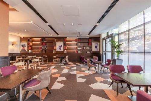 a waiting room with tables and chairs and books at Radisson Blu Hotel, Paris Boulogne in Boulogne-Billancourt