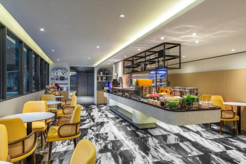 a restaurant with yellow chairs and tables and a counter at Best Western Ratchada Hotel in Bangkok