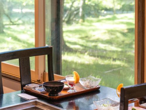 a wooden tray with a drink on a table with a window at Okunikko Konishi Hotel in Nikko