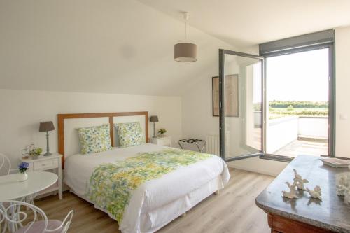 une chambre blanche avec un lit et une grande fenêtre dans l'établissement Coeur et Nature, à Colembert