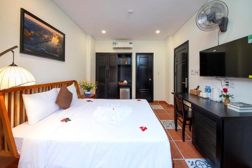 a bedroom with a bed with a desk and a television at Du Yen Hoi An Villa in Hoi An