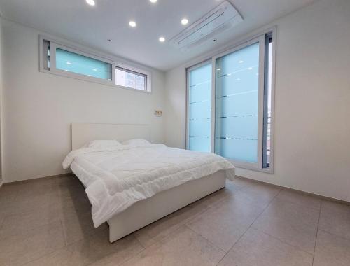 een witte slaapkamer met een bed en een groot raam bij Luxury Terrace House in Seoul